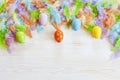 Milticolor bird feathers and Easter eggs decoration. Easter concept. Top view, close up, flat lay on white wooden background Royalty Free Stock Photo