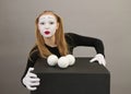 Mime artist near black cube with juggling balls. Circus clown woman