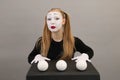 Mime artist near black cube with juggling balls. Circus clown woman