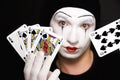 Mime with playing cards on black background