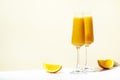 Mimosa alcohol cocktail drink with orange juice and cold dry champagne or sparkling wine in glasses. Beige background, hard light