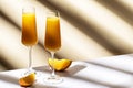 Mimosa alcohol cocktail drink with orange juice and cold dry champagne or sparkling wine in glasses. Beige background, hard light