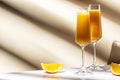 Mimosa alcohol cocktail drink with orange juice and cold dry champagne or sparkling wine in glasses. Beige background, hard light