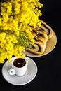 Mimosa, cup of coffee and poppy seed strudel on a black background