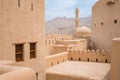 Minaret, dome and walls of medievel arabian fort of Nizwa, Oman. Hot day in arabian desert city. Middle east military