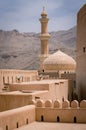 Minaret, dome and walls of medievel arabian fort of Nizwa, Oman. Hot day in arabian desert city.