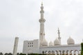 Minaret and domes of white Grand Mosque against white cloudy sky, also called Sheikh Zayed Grand Mosque, inspired by Persian,