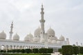 Minaret and domes of white Grand Mosque against white cloudy sky, also called Sheikh Zayed Grand Mosque, inspired by Persian,