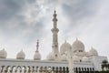 Minaret and domes of white Grand Mosque against white cloudy sky, also called Sheikh Zayed Grand Mosque, inspired by Persian,