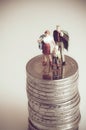 Minatue family on pile of coins. Family budget concept Royalty Free Stock Photo