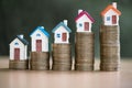 Minature houses resting on coin stacks, concept for property ladder, mortgage and real estate investment