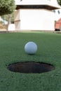 Miniature or mini golf hole close up with ball in center on green artificial turf outdoors portrait view Royalty Free Stock Photo
