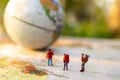 Minature people: traveling with a backpack standing on vintage world map and globe, Travel and vacation concept.