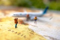 Minature people: traveling with a backpack standing on vintage world map and plane, Travel and vacation concept.
