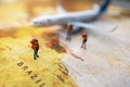 Minature people: traveling with a backpack standing on vintage world map and plane, Travel and vacation concept