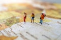 Minature people: traveling with a backpack standing on vintage world map, Travel and vacation concept