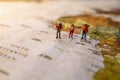 Minature people: traveling with a backpack standing on vintage world map, Travel and vacation concept