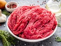 Mince beef, ground meat with ingredients for cooking on dark gray background, side view, close up