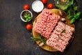 Minced beef and pork on a cutting board, raw meat and various spices on a stone or slate background.