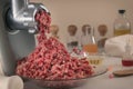 Minced meat comes out of a meat grinder against the background of glassware of a chemical laboratory.