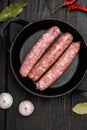 Minced meat sausages, on frying cast iron pan, on black wooden table background, top view flat lay Royalty Free Stock Photo