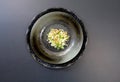 Minced scallion, shallots, and ginger in a black bowl set on a black background