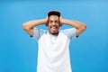 Mind blowing out from lots of information. Portrait of distressed African American male student in t-shirt holding hands