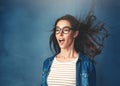 Mind blown. Studio shot of a young woman with air being blown in her face against a blue background.