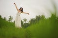 Mind and body connection with nature - middle aged attractive and happy Asian Chinese woman in Summer dress enjoying idyllic