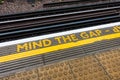 A mind the gap yellow painted floor sign.