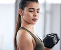 Mind over matter. a young woman working out with dumbbell weights in a gym.