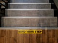 Mind Your Step sign printed on the tile floor over the staircase