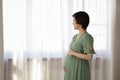Mindful expectant mother look outside of window lost in dreams Royalty Free Stock Photo