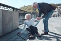 Mindful man helping elderly female stranger to stand up