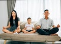 Mindful meditation on a sofa as a young family practices yoga together