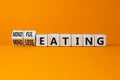 Mindful or mindless eating symbol. Turned wooden cubes and changed words mindless eating to mindful eating. Beautiful orange