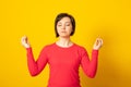 Mindful peaceful woman meditates indoor, keeps hands in mudra gesture, has eyes closed, tries to relax after long hours of work