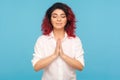 Mindfulness practice. Portrait of peaceful hipster woman with fancy red hair keeping hands in namaste