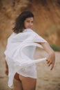 Mindfulness and relaxation. Joyful boho girl in white summer dress walking on beach. Hands with dress closeup. Carefree young