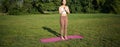 Mindfulness and wellbeing. Young woman doing yoga, standing on mat in park, making asana, meditating on fresh air, urban Royalty Free Stock Photo