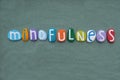 Mindfulness word composed with multi colored stone letters over green sand Royalty Free Stock Photo