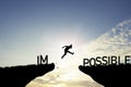 Mindset concept ,Silhouette man jumping over impossible and possible  wording on cliff with cloud sky and sunlight Royalty Free Stock Photo