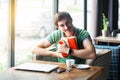 This is mine. Young happy proud businessman in green t-shirt sitting, holding and hug his favorite big red gift box, looking at Royalty Free Stock Photo