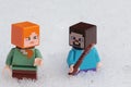 Minecraft LEGO character figures of Steve with shovel and Alex standing in real deep snow