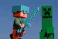 Minecraft LEGO figure of Alex in helmet with diamond sword, attacking Creeper explosive creature