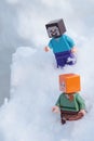 Minecraft LEGO figures of Steve and Alex walking in real deep snow.