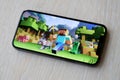 Minecraft mobile iOS game on iPhone 15 smartphone screen on wooden table during mobile gameplay