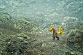 Miner carries baskets with sulphur in fumes of toxic volcanic gas from sulphur mines