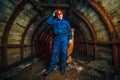 A miner in a coal mine stands near a trolley. Copy space. Passages and corridors in a coal mine.