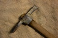 Miner hammer like pickaxe or mattock on bagging fabric background. Closeup view of rustic old hand tool for hard working to